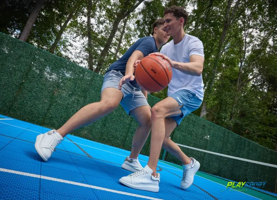 Two players in a one-on-one game on a blue PlaySport modular backyard basketball court in Atlanta, GA