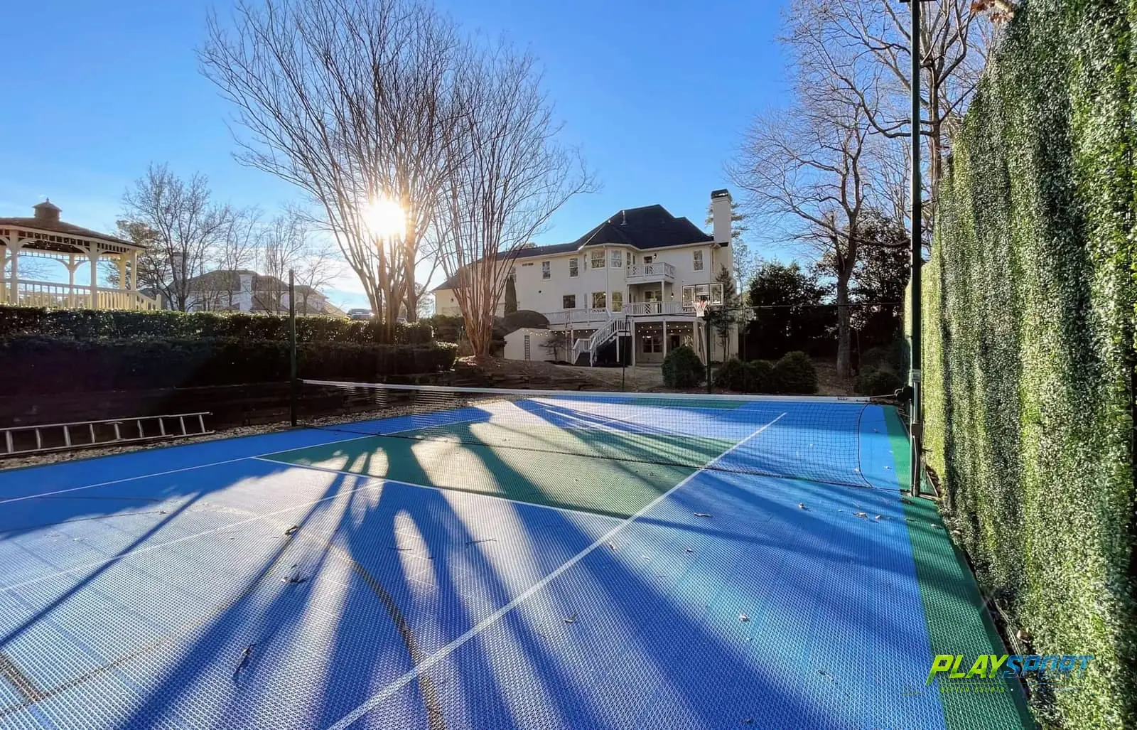 Blue and teal modular backyard tennis court behind a colonial home