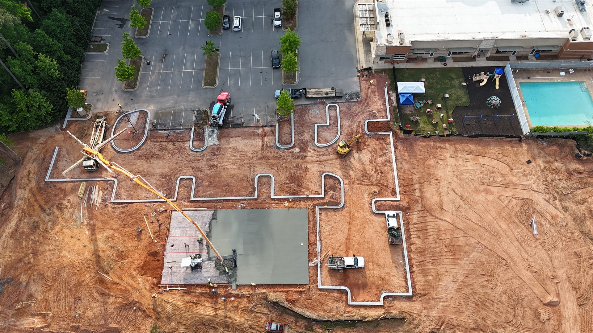 Aerial view of a sport court under construction — fresh concrete base being poured before PlaySport modular tiles are installed