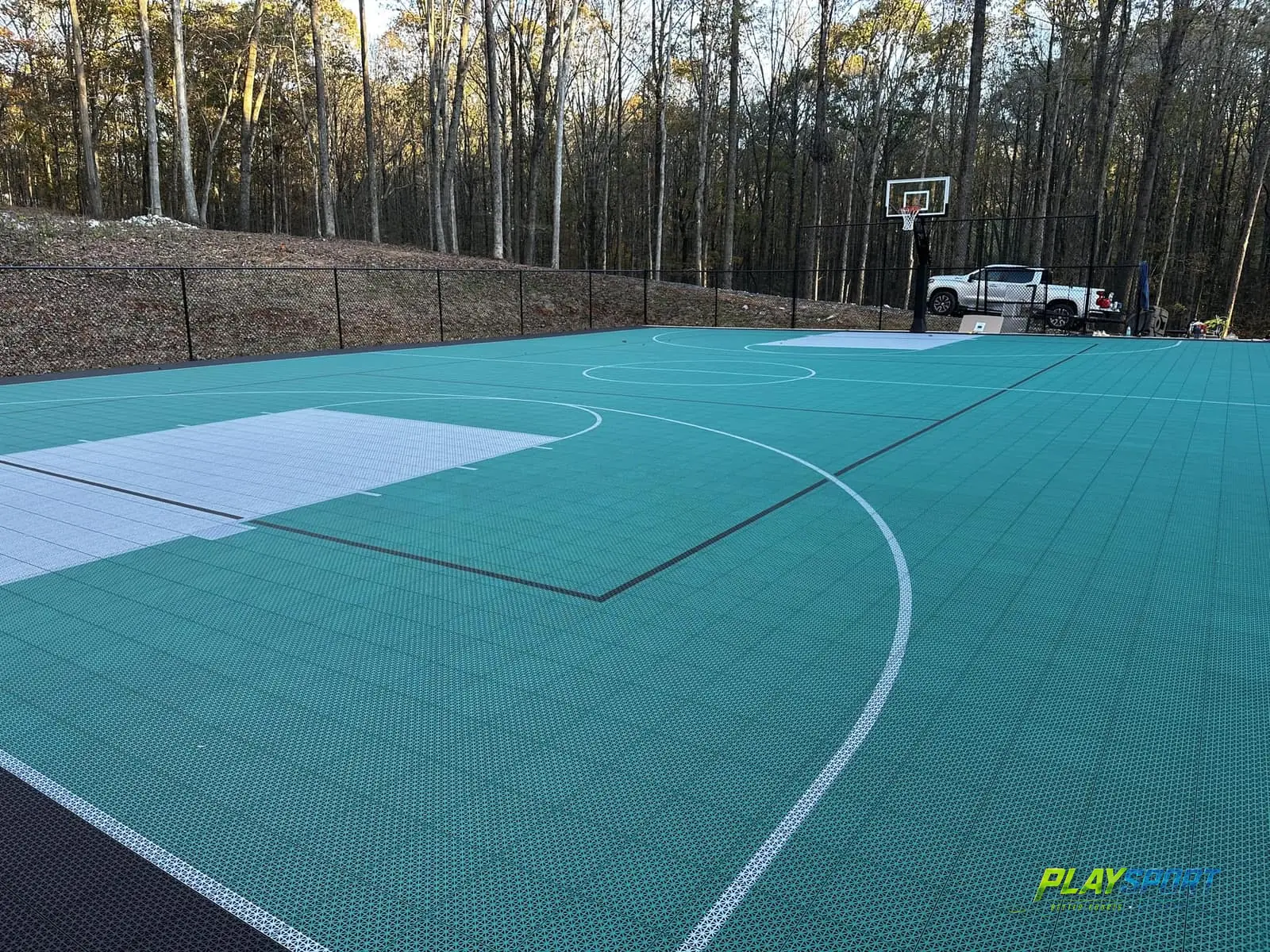 Full-size teal modular multi-sport court with basketball hoops and game lines