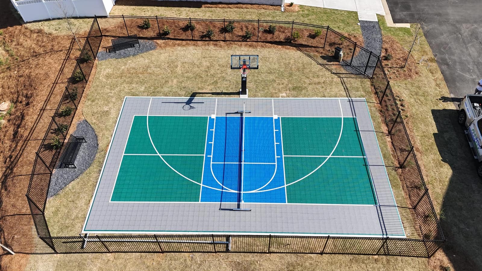 Completed basketball court — green and blue tiles with iron fence