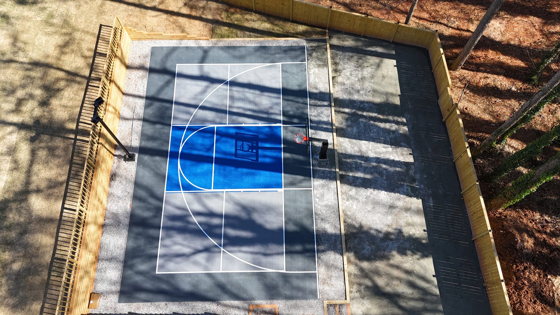 Basketball court — grey and blue tiles with wooden fence enclosure