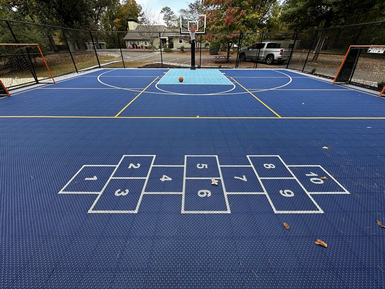 Blue family multi-sport court with basketball hoop, hockey goals and hopscotch markings