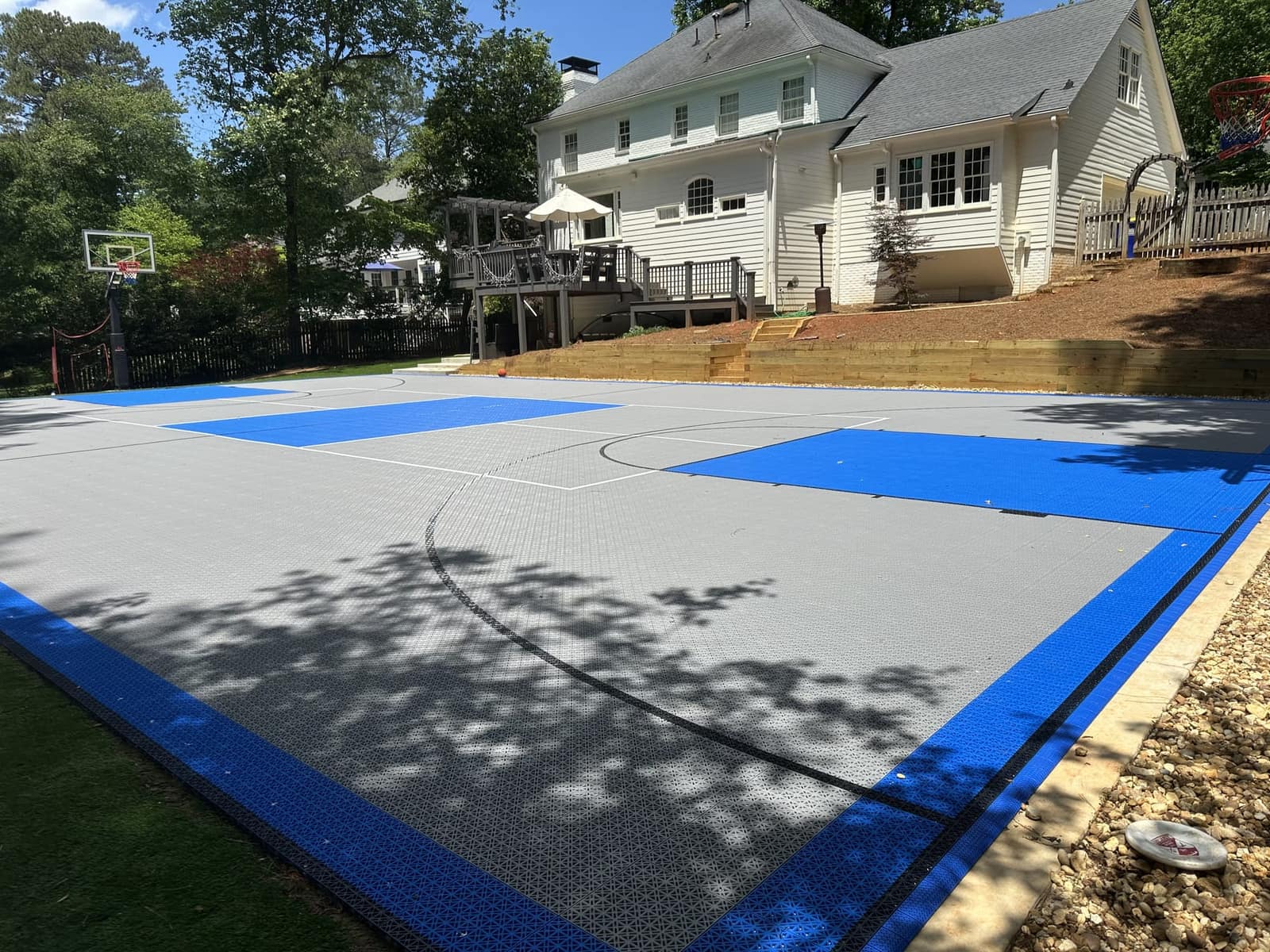 Grey and blue Core tile basketball court below a terraced backyard