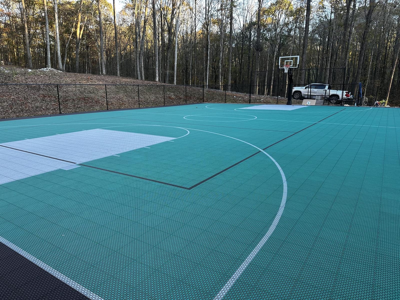 Full-size teal multi-sport court with basketball hoops and game lines