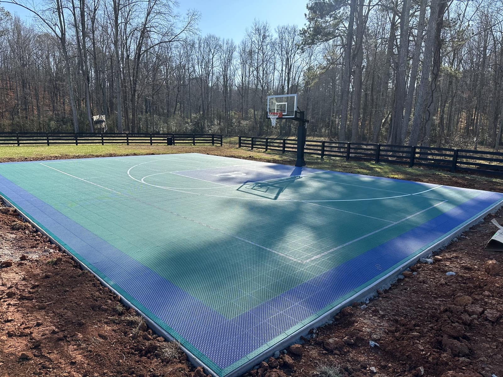 Green and periwinkle blue backyard basketball half court, freshly installed