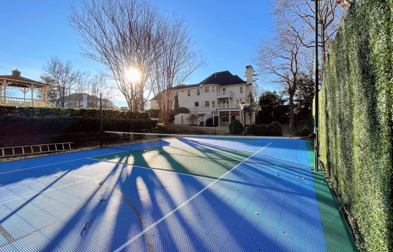 Blue and teal backyard tennis court behind a colonial home