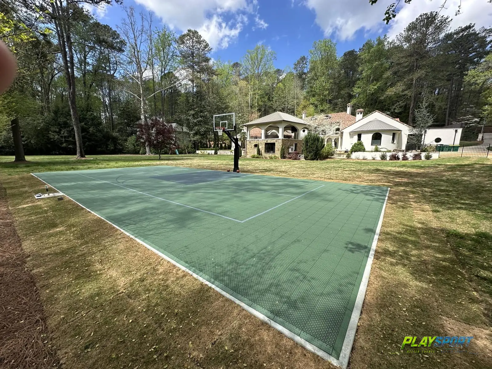 Green modular multi-sport game court on an estate lawn