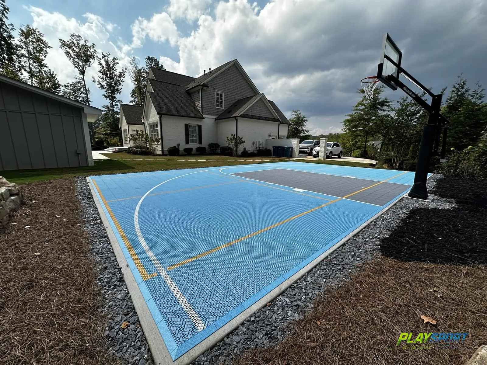 Sky blue modular backyard half court with a charcoal key and adjustable hoop